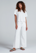 Person wearing a white t-shirt and wide-leg pants on a plain background