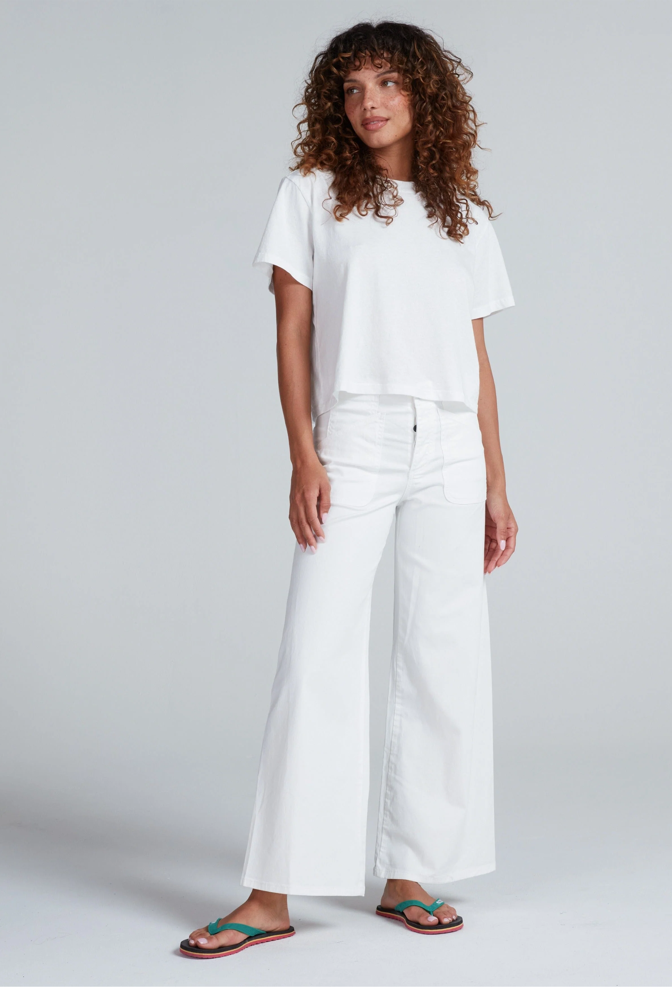 Person wearing a white t-shirt and wide-leg pants on a plain background