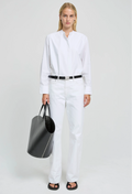 Person wearing a white shirt and pants holding a black bag on a white background