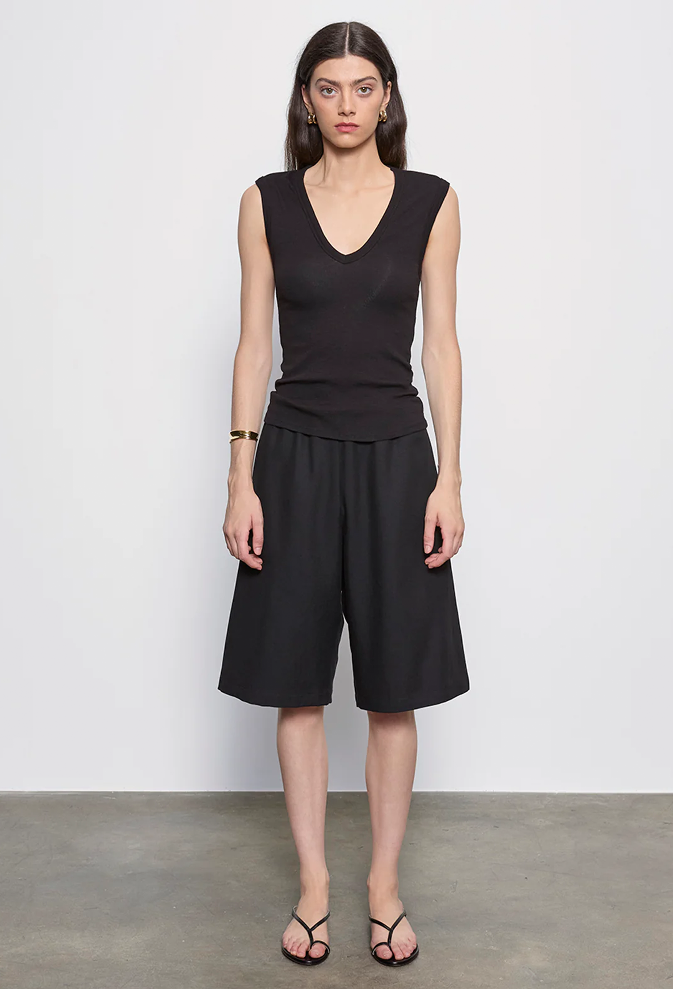 Woman wearing a black sleeveless top and black shorts against a white background