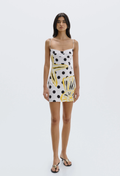 Woman wearing a polka dot dress with abstract patterns on a white background