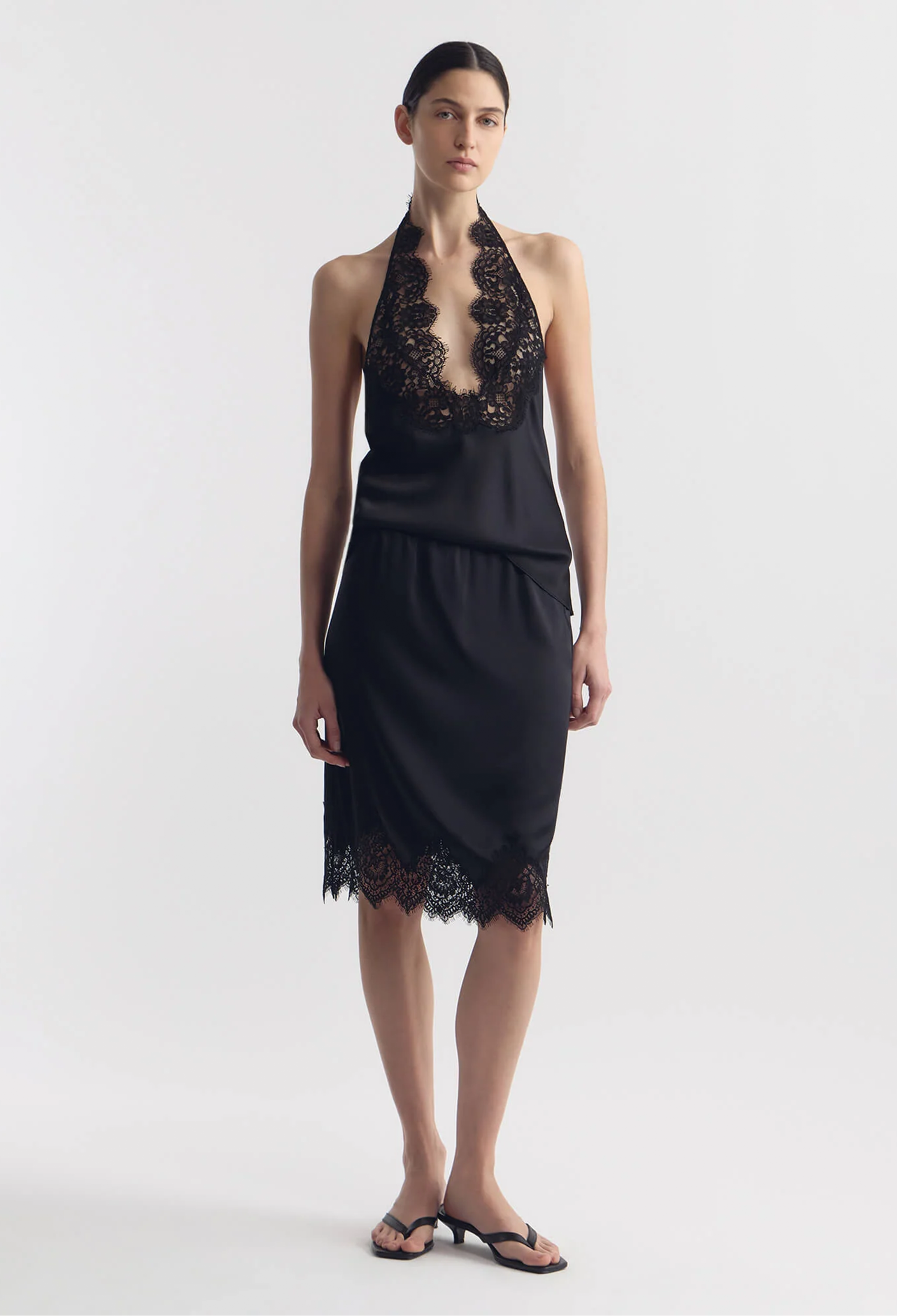 model wearing a black silk tank and matching skirt with lace hem on a white background