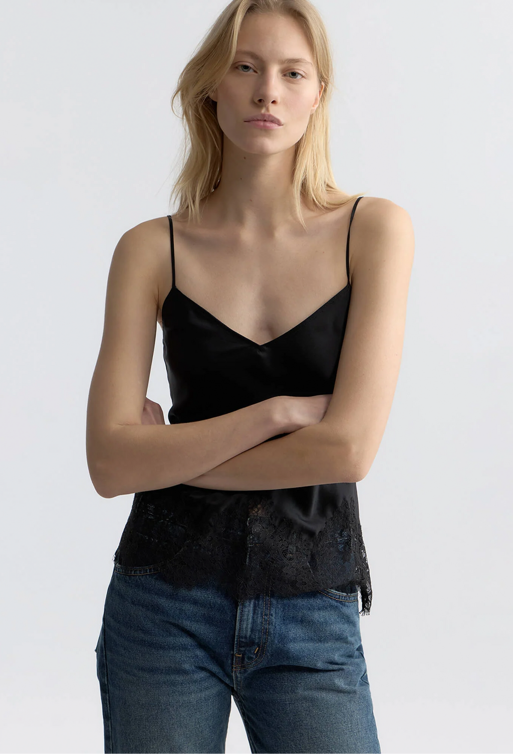 model wearing a black silk tank with lace hem on a white background