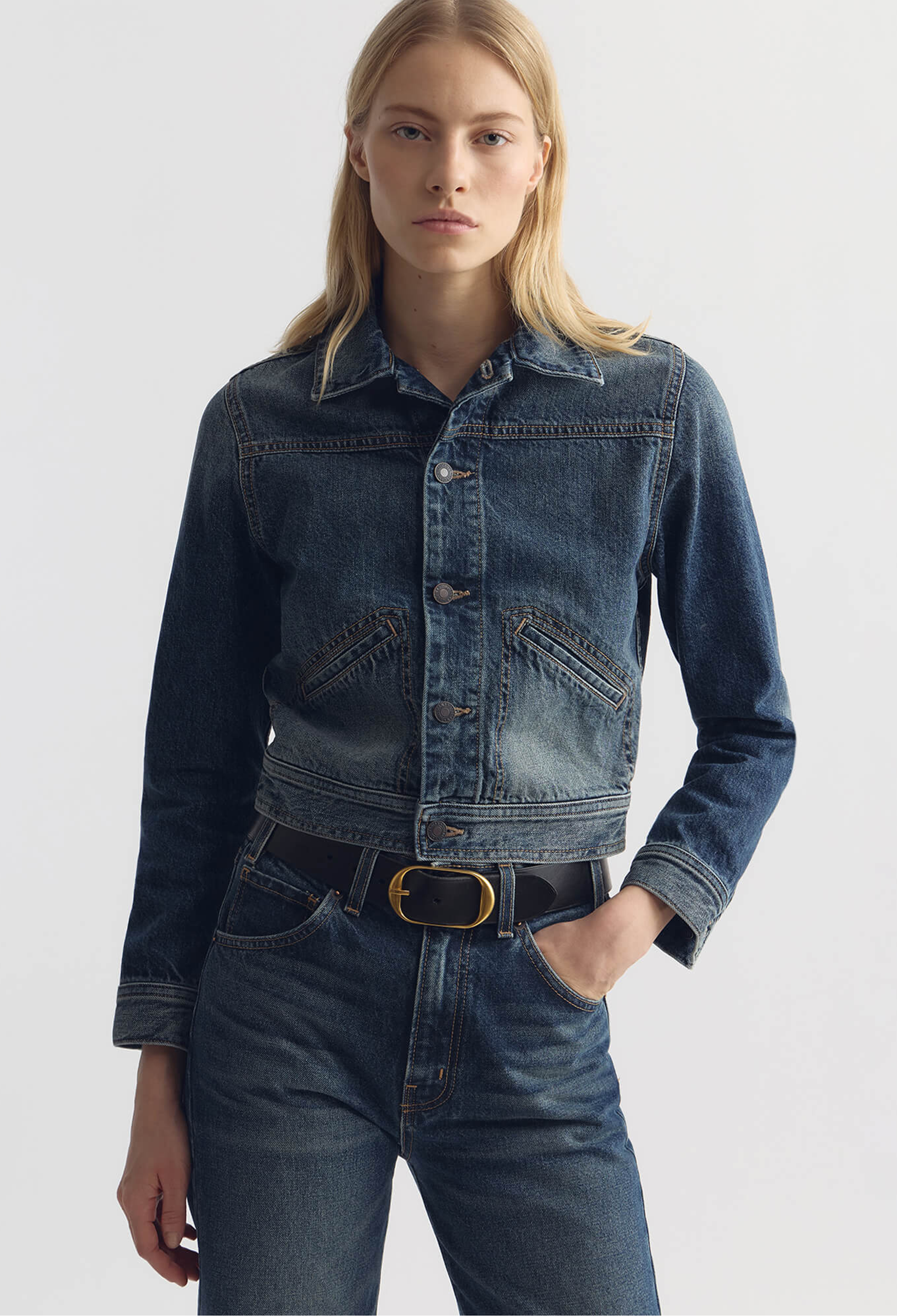 Woman wearing a blue denim jacket and jeans on a white background