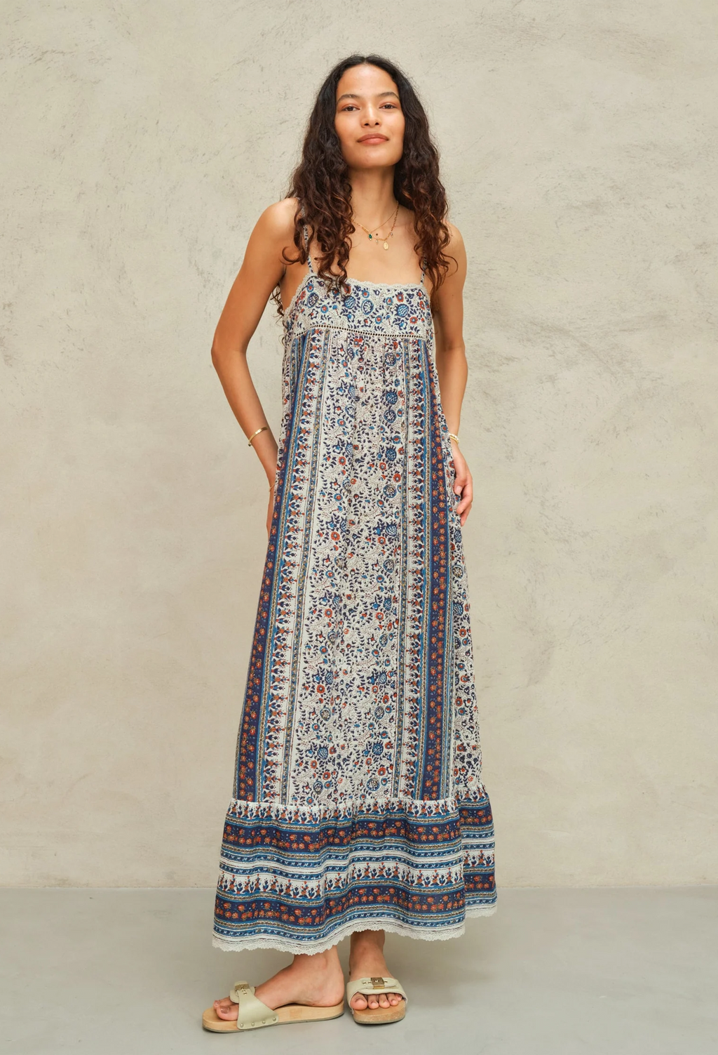 Woman wearing a long, patterned dress against a plain background
