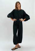 Person wearing a black outfit with wide sleeves on a white background