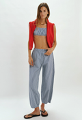 Woman wearing a red jacket, blue patterned top, and light blue pants on a white background