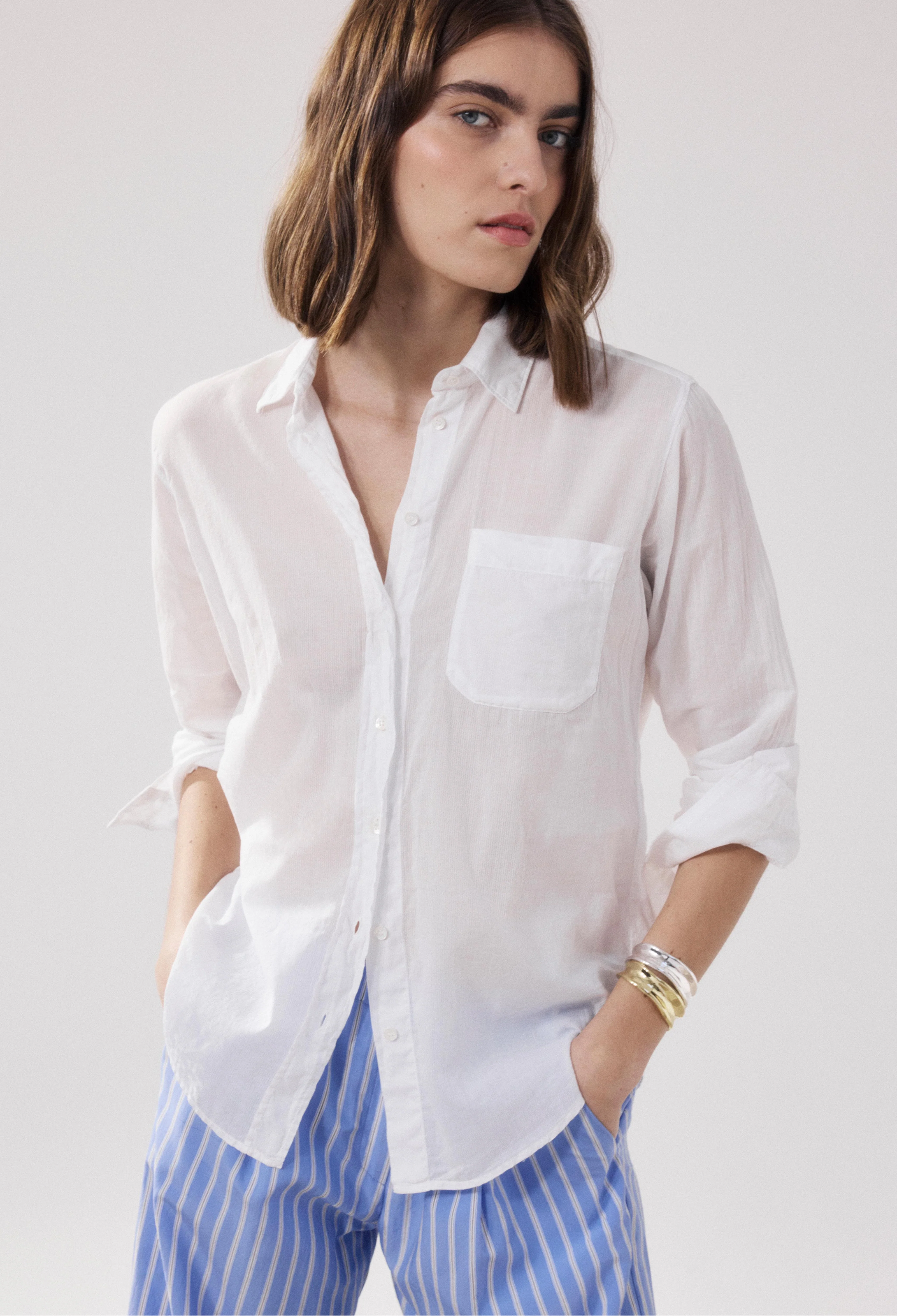 Woman wearing a white shirt and blue striped pants on a plain background