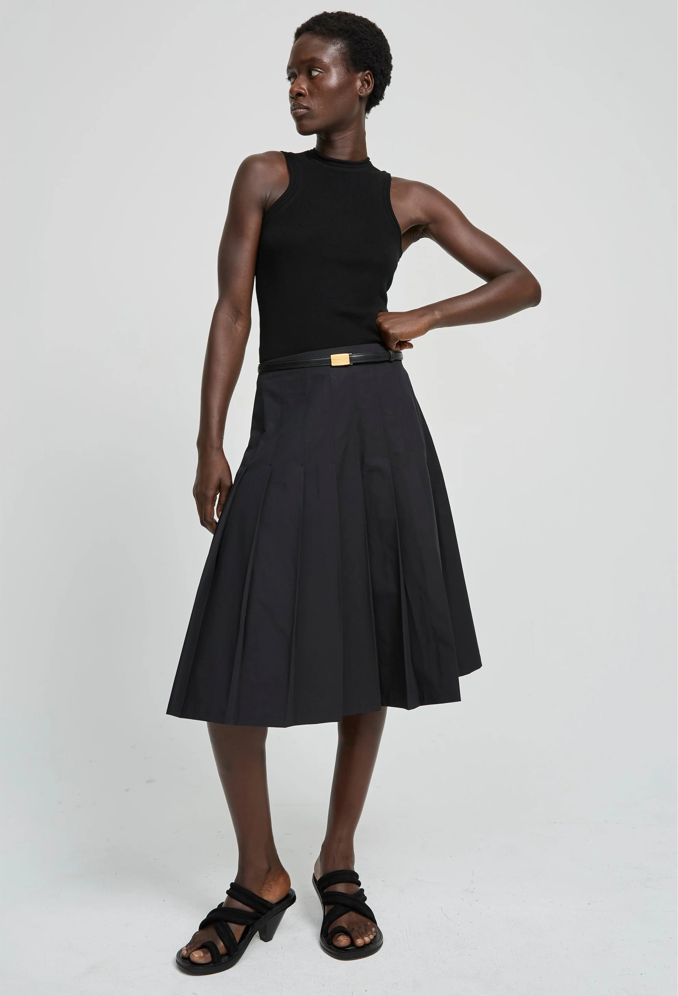 Woman wearing a black sleeveless top and black skirt on a white background