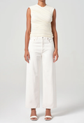 Person wearing a white sleeveless top and wide-leg pants on a plain background