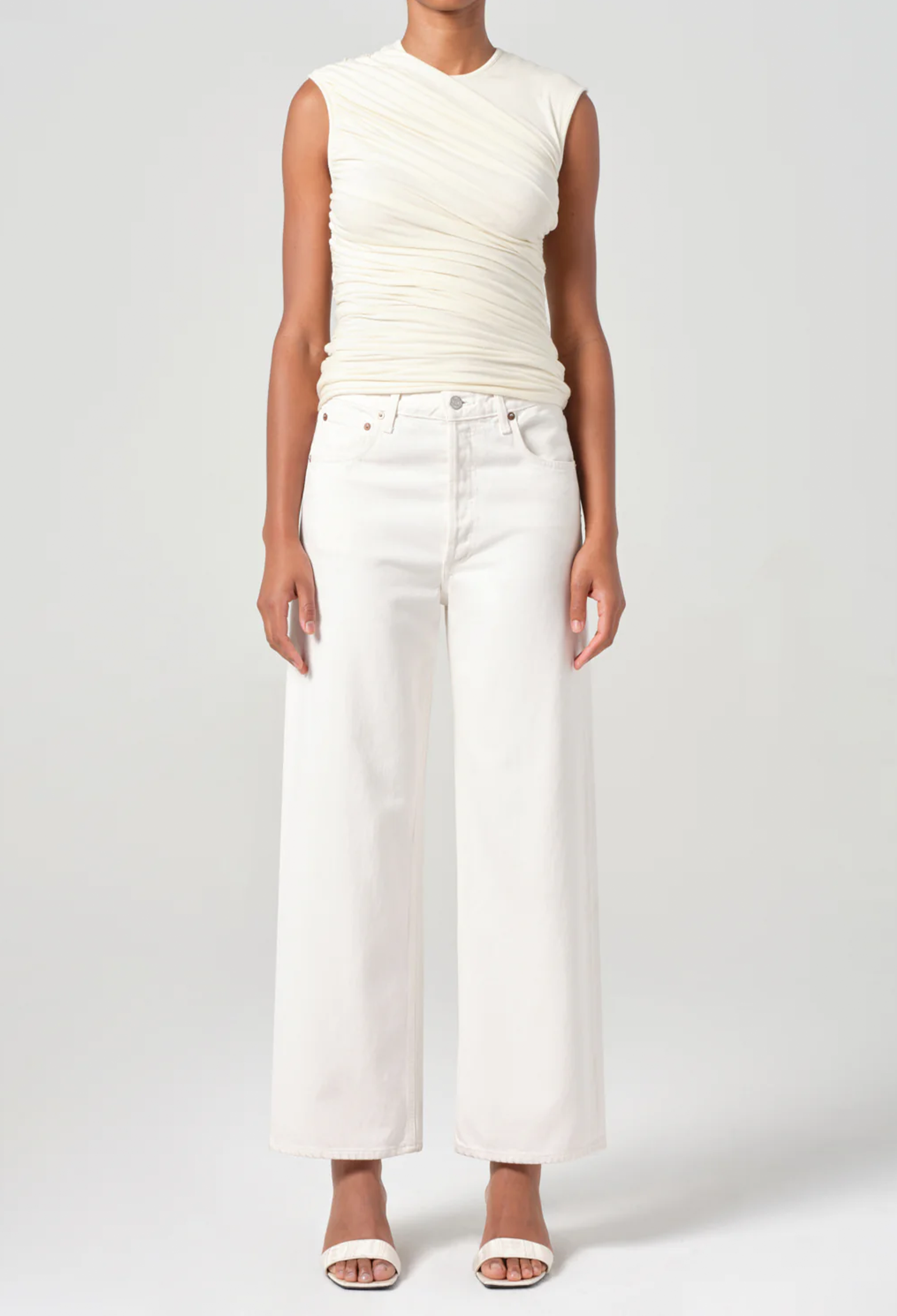 Person wearing a white sleeveless top and wide-leg pants on a plain background