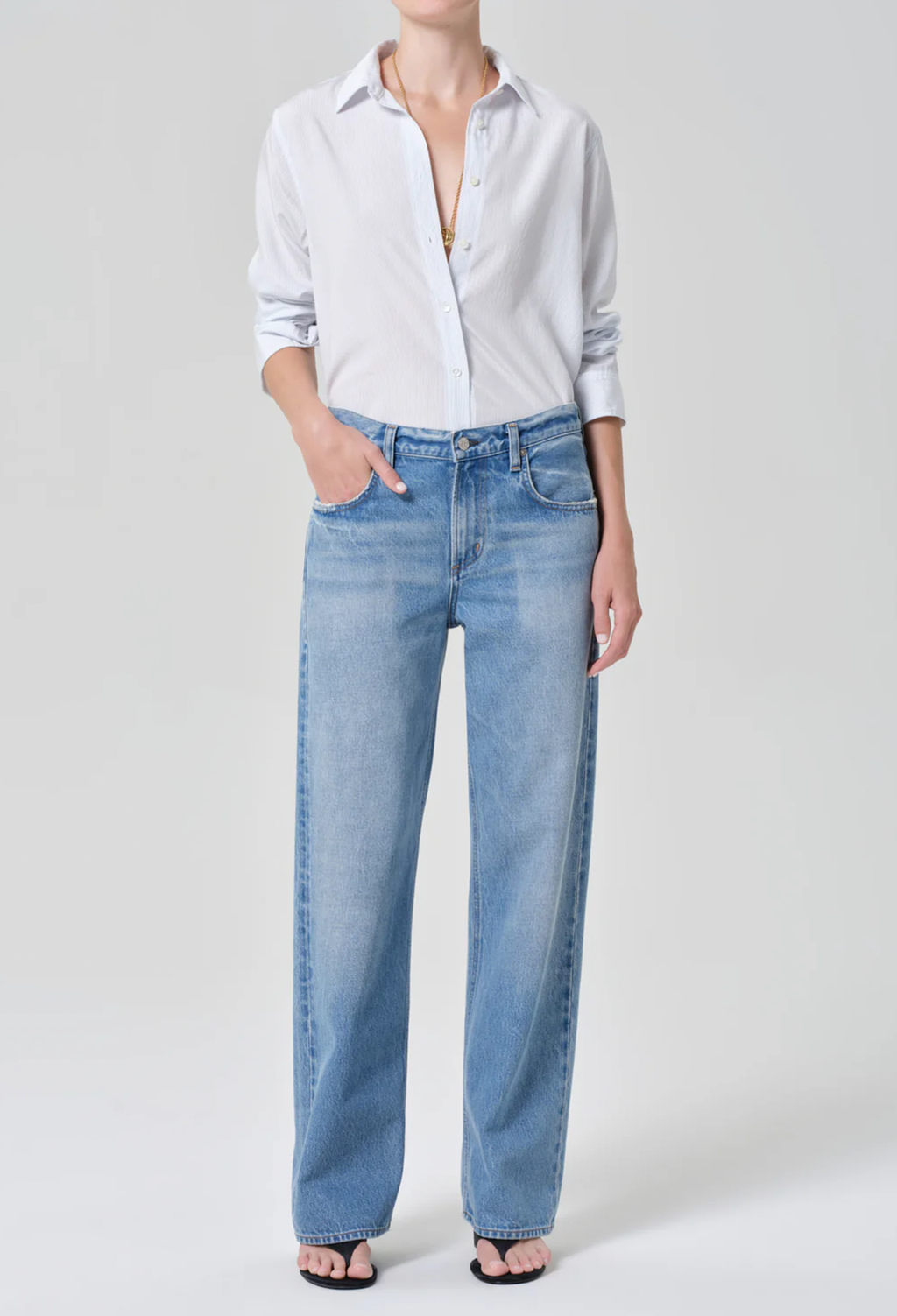 Person wearing a light blue shirt and jeans on a white background