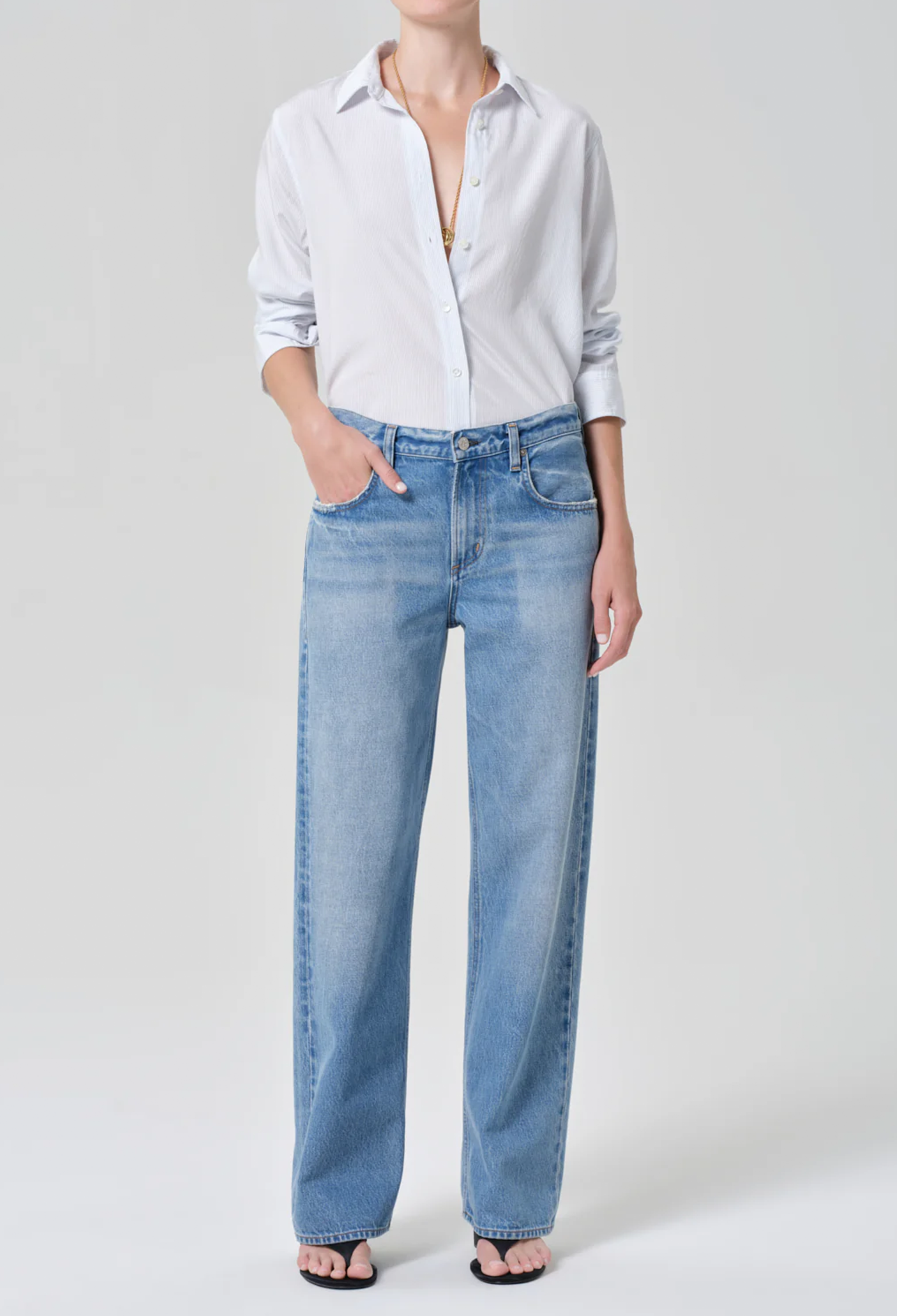 Person wearing a light blue shirt and jeans on a white background