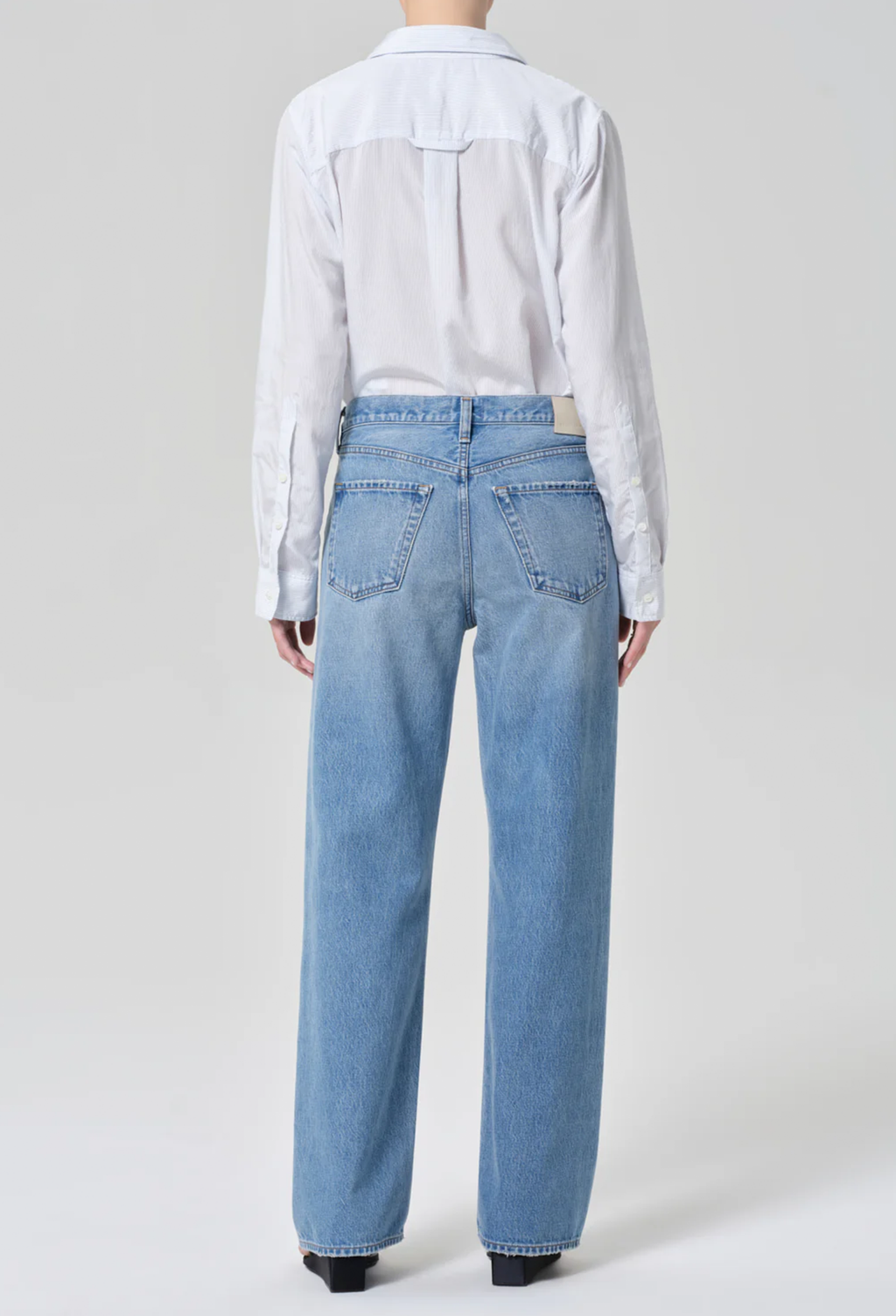 Person wearing a light blue shirt and jeans on a white background