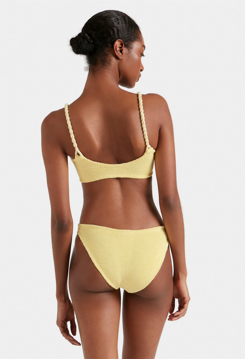 Woman wearing a yellow bikini set on a plain background