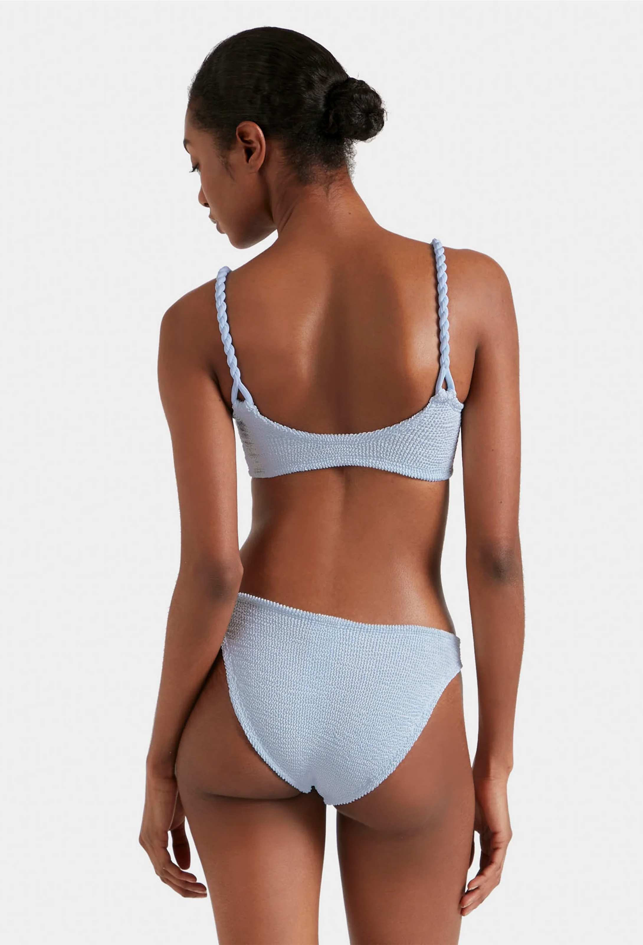 Woman wearing a light blue bikini set on a white background
