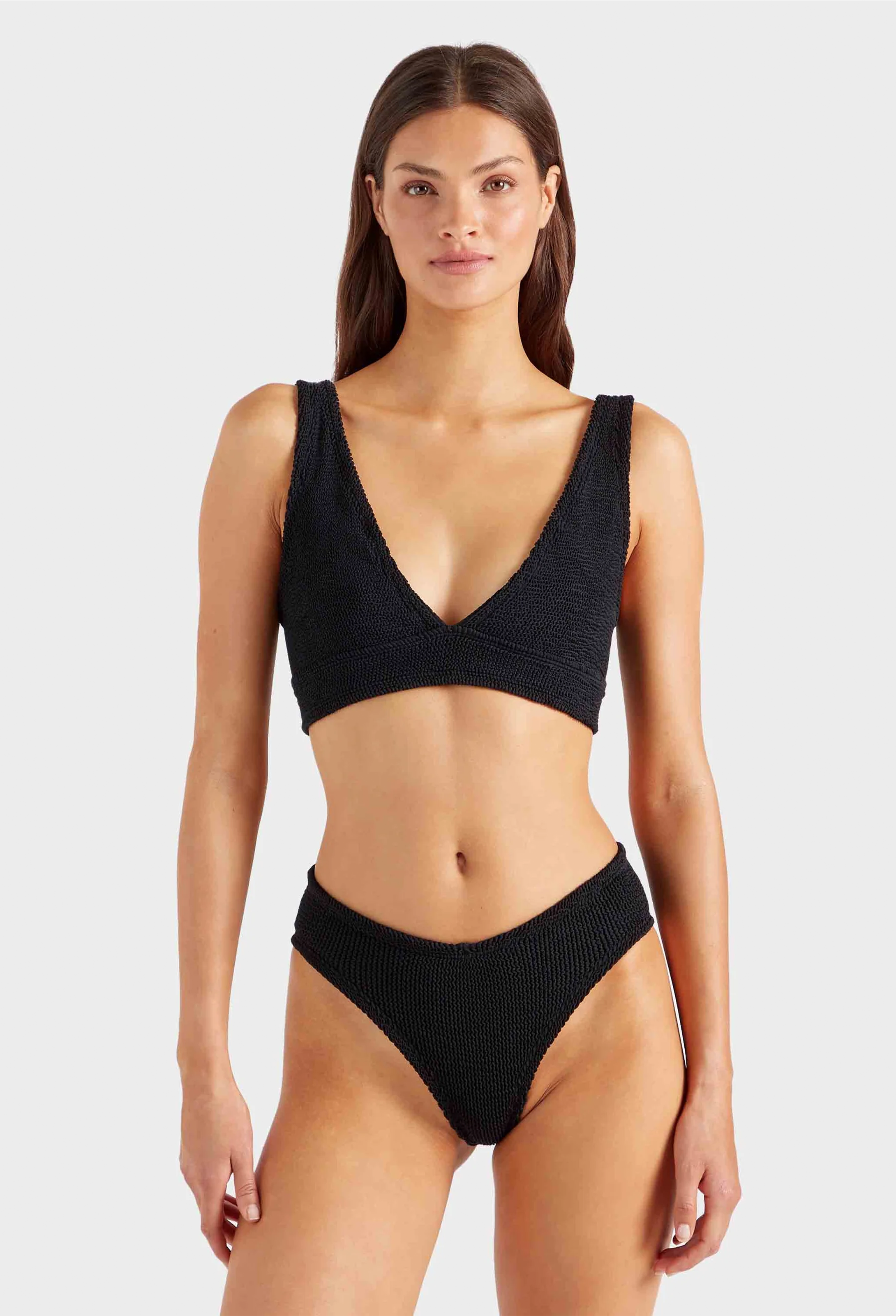 Woman wearing a black bikini set on a light gray background