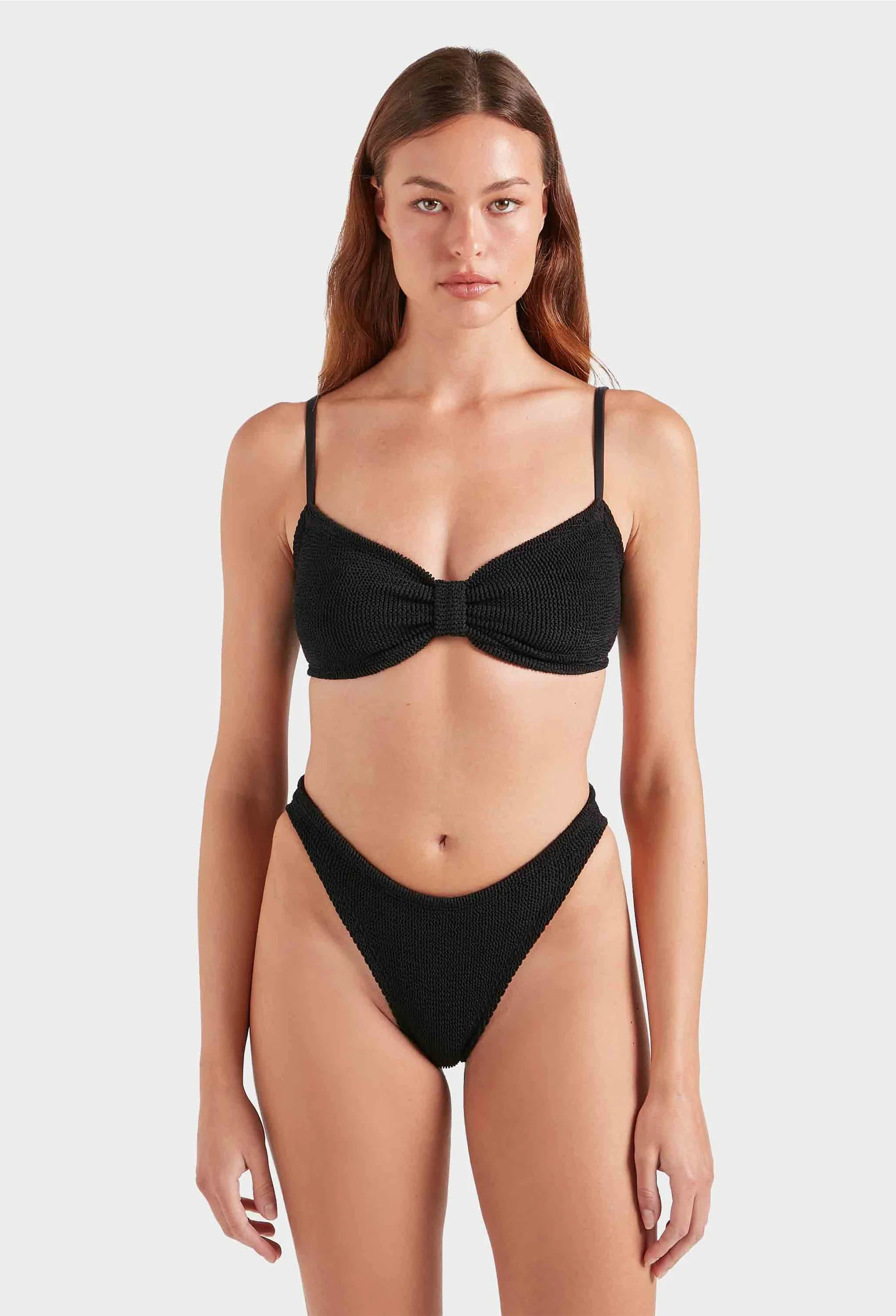 Woman wearing a black bikini against a white background
