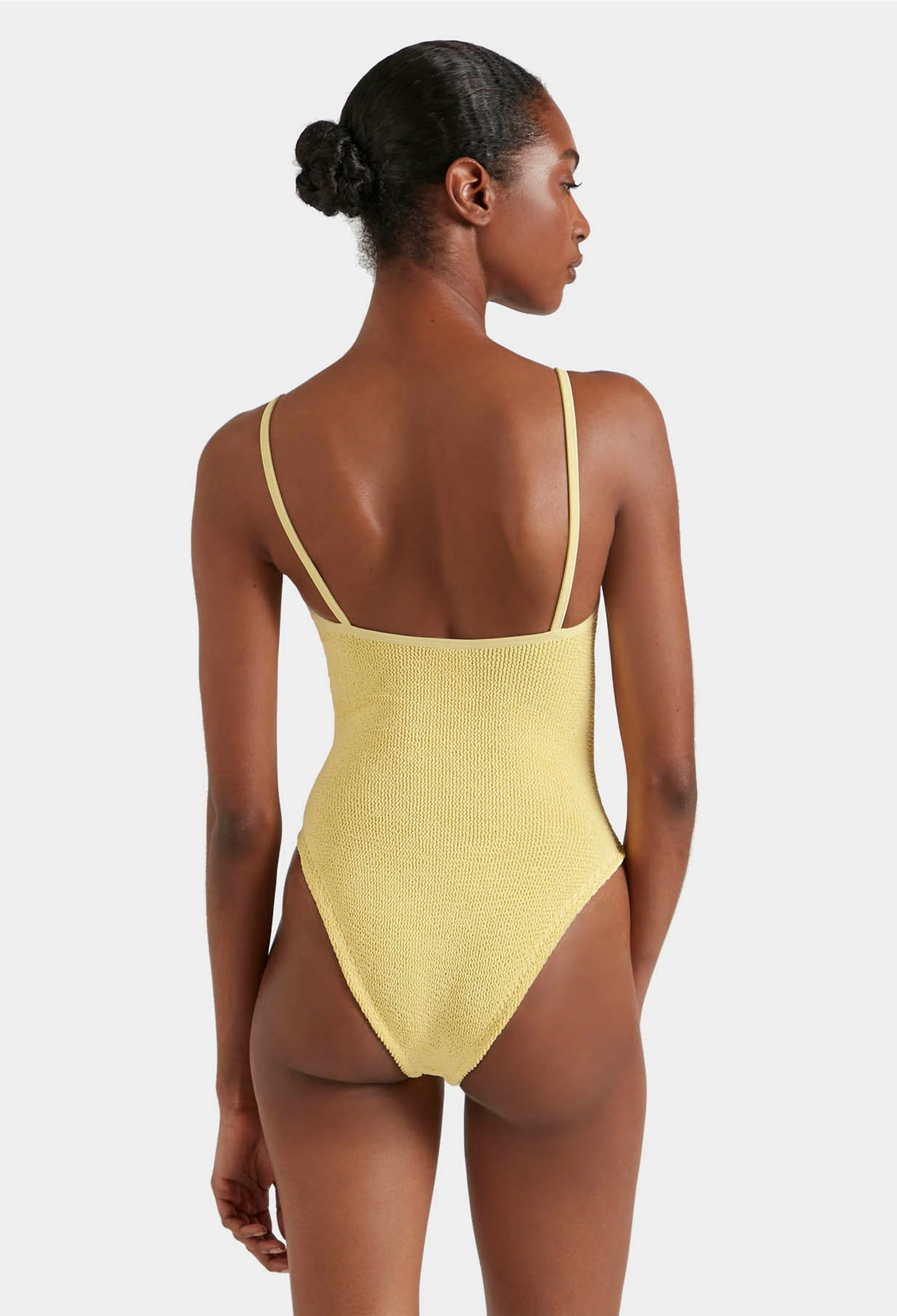 Woman wearing a yellow swimsuit on a white background