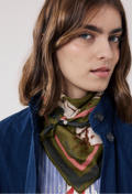 Woman wearing a patterned scarf around her neck with a plain background