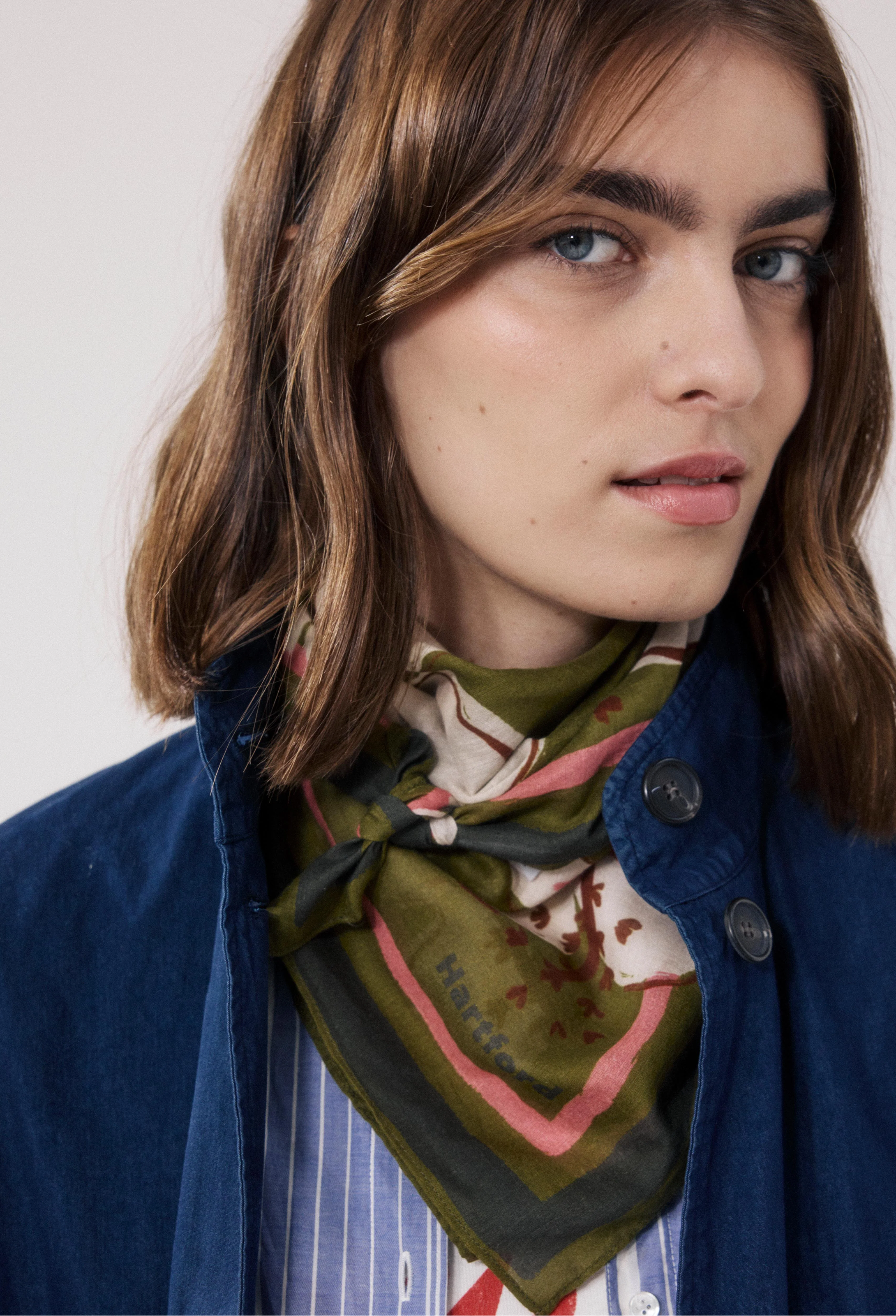 Woman wearing a patterned scarf around her neck with a plain background