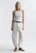 Woman wearing a white sleeveless top and white pants on a plain background