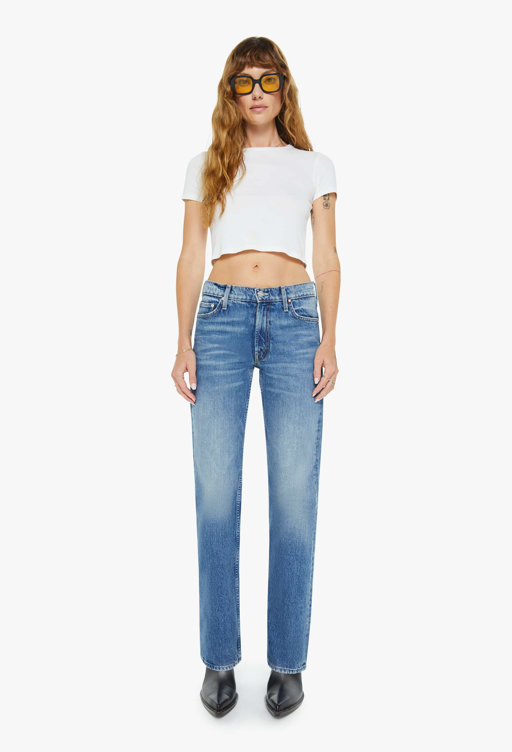 Woman wearing a white crop top and blue jeans on a white background