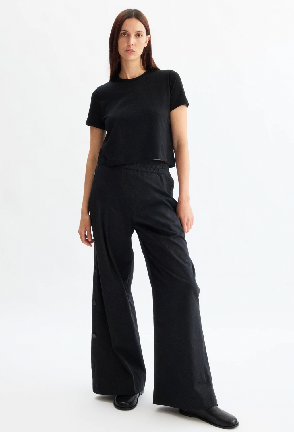 Woman wearing a black outfit with wide-leg pants on a white background