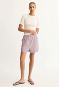 Woman wearing a white top and striped shorts on a plain background