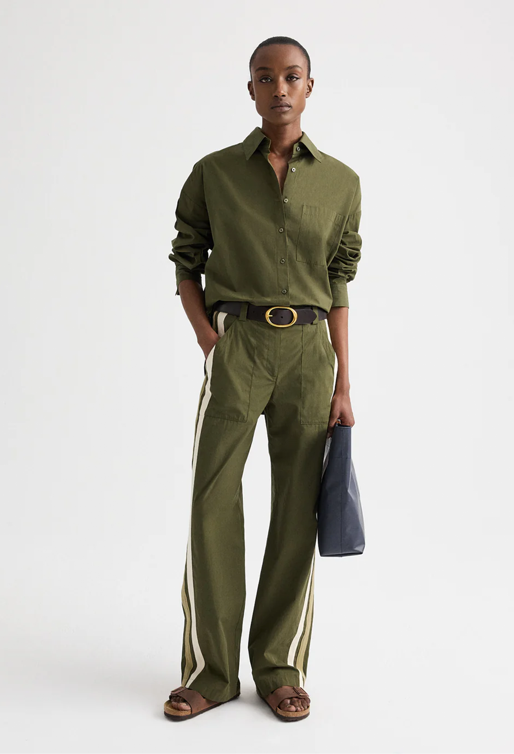 Person wearing a green shirt and pants with a belt, standing against a white background