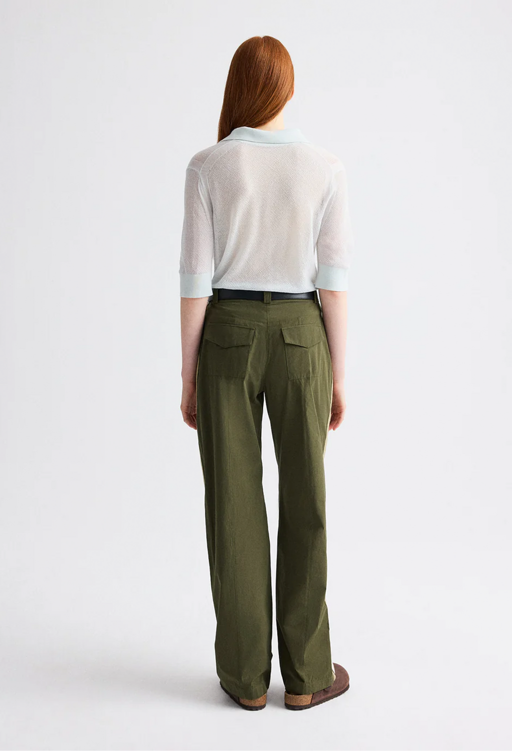 Person wearing a white shirt and green pants on a white background