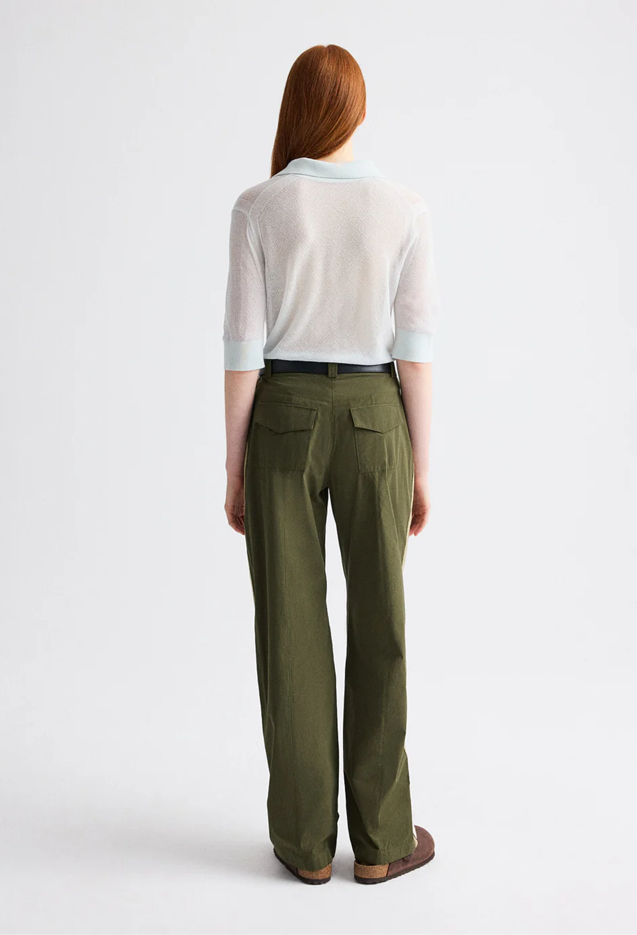 Person wearing a white shirt and green pants on a white background