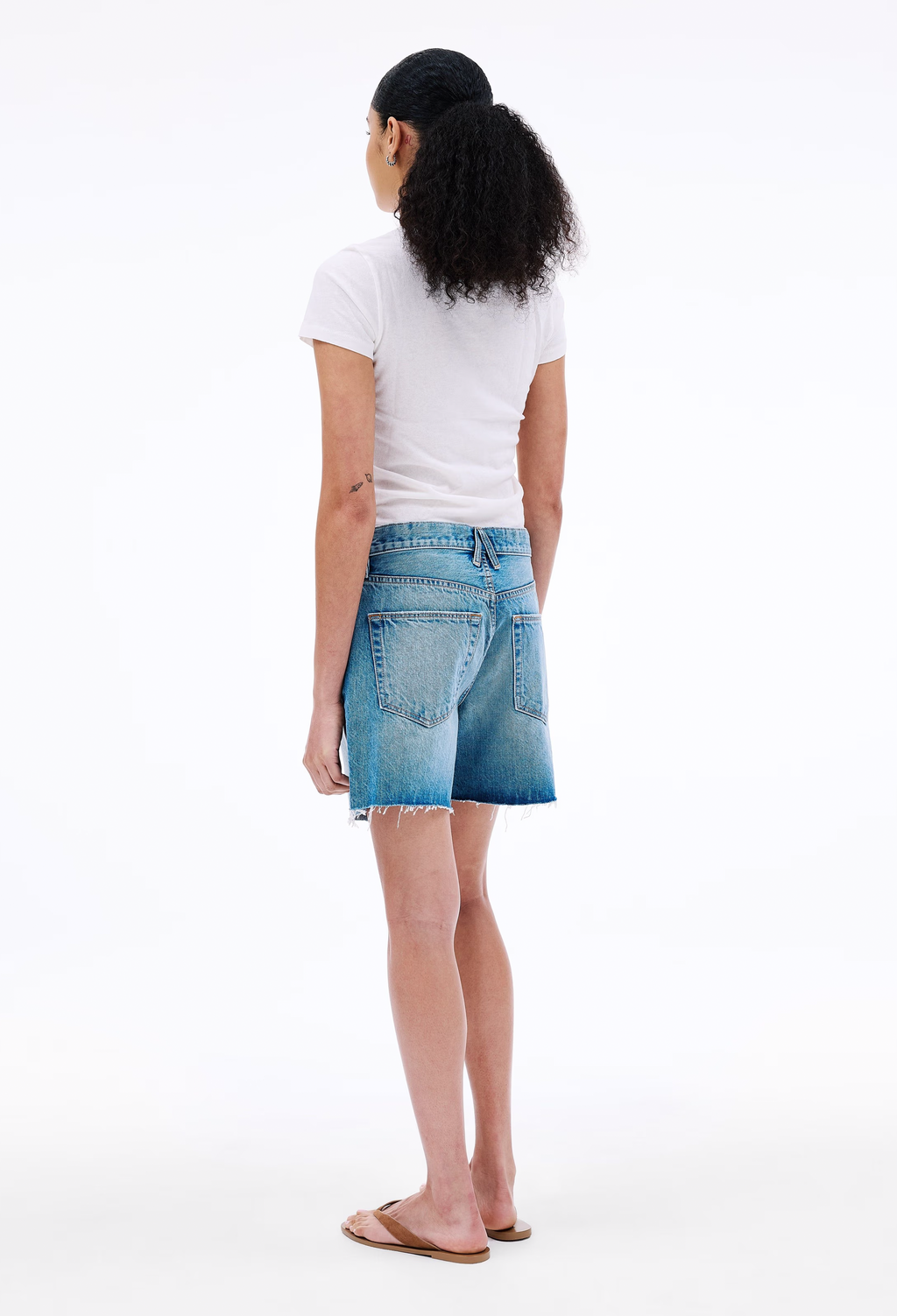 Person wearing a white t-shirt and blue denim skirt on a white background