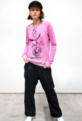 Person wearing a pink sweater with a graphic design and black pants on a white background