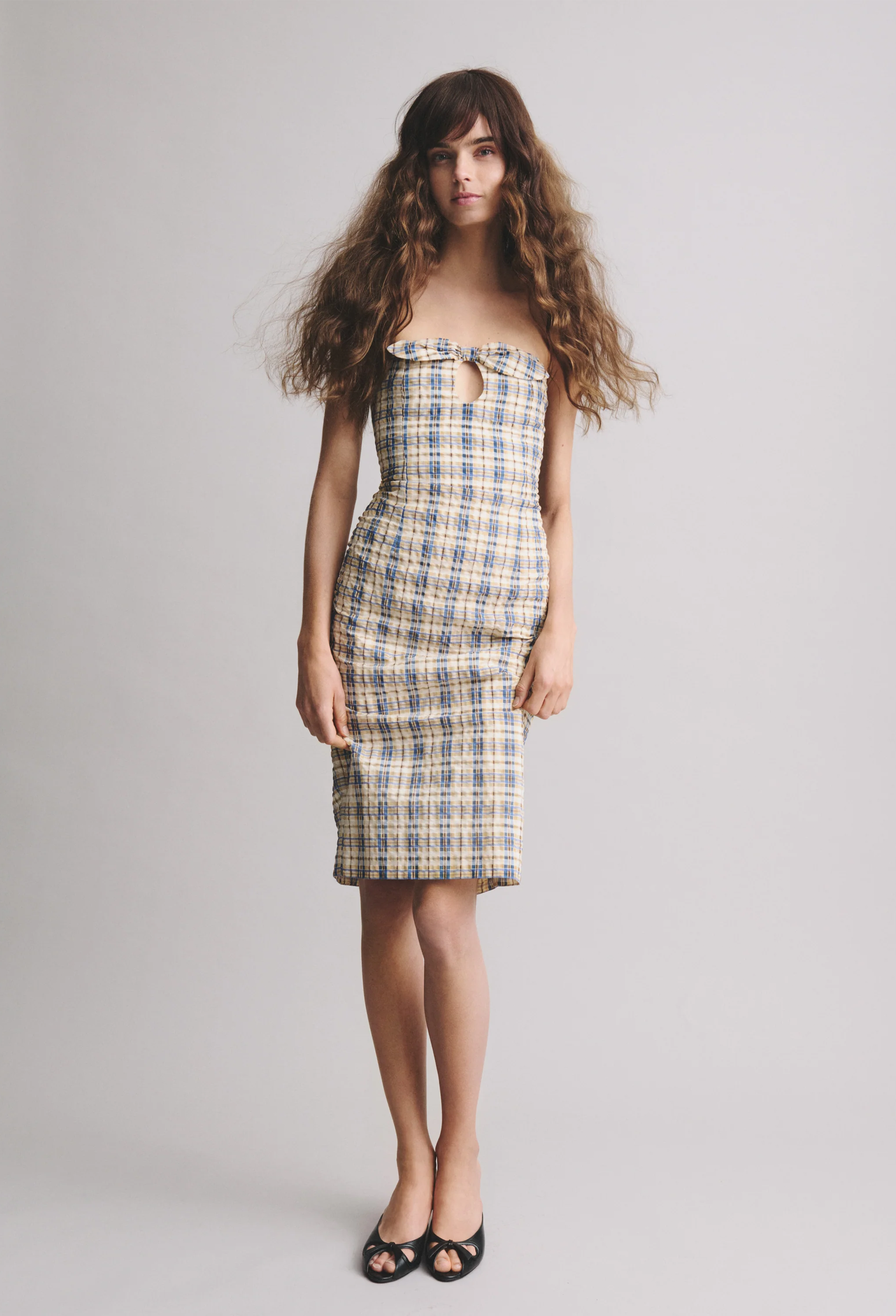 model wearing a midi dress with blue and yellow check on a white background