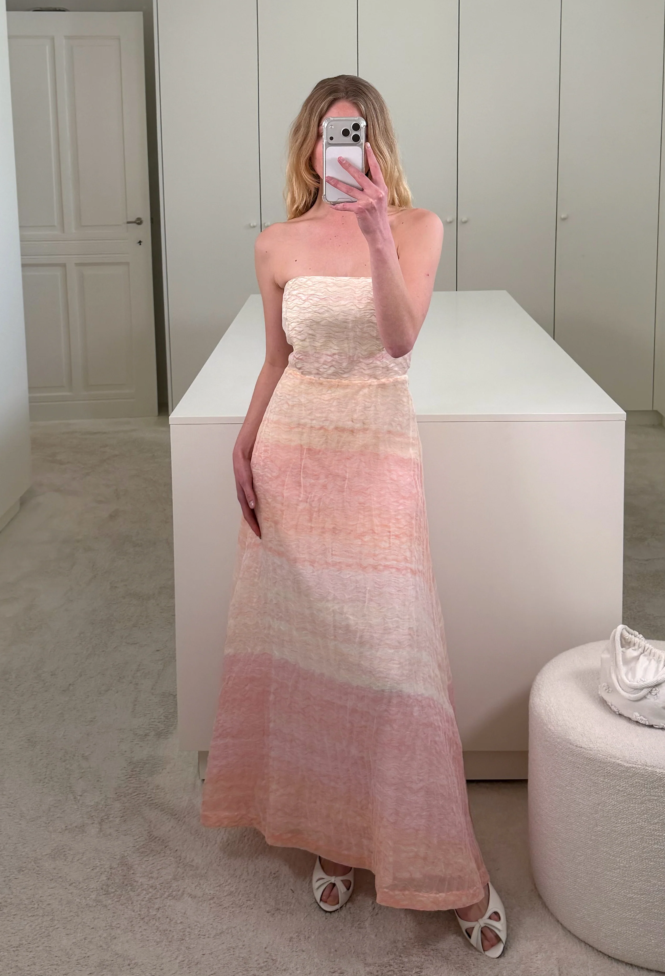 woman wearing a strapless pink white and orange maxi dress inside a closet