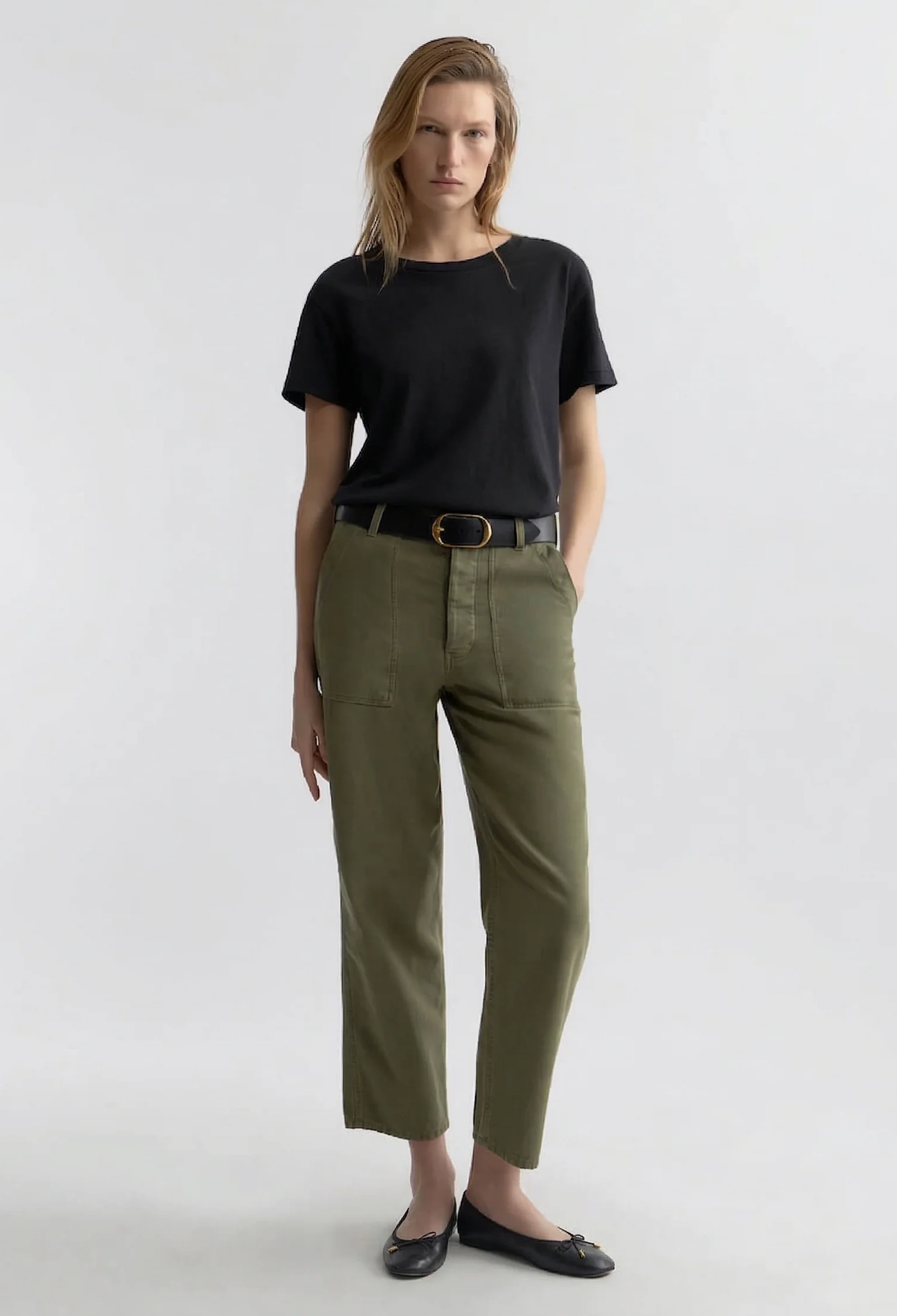 model wearing a black tee and olive green pants on a white background