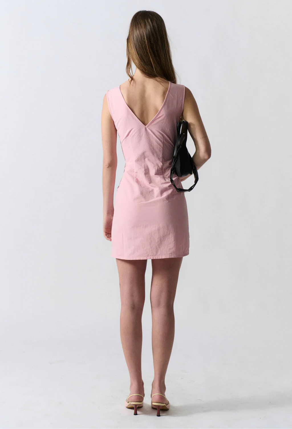 model wearing a sleeveless mini pink dress on a white background