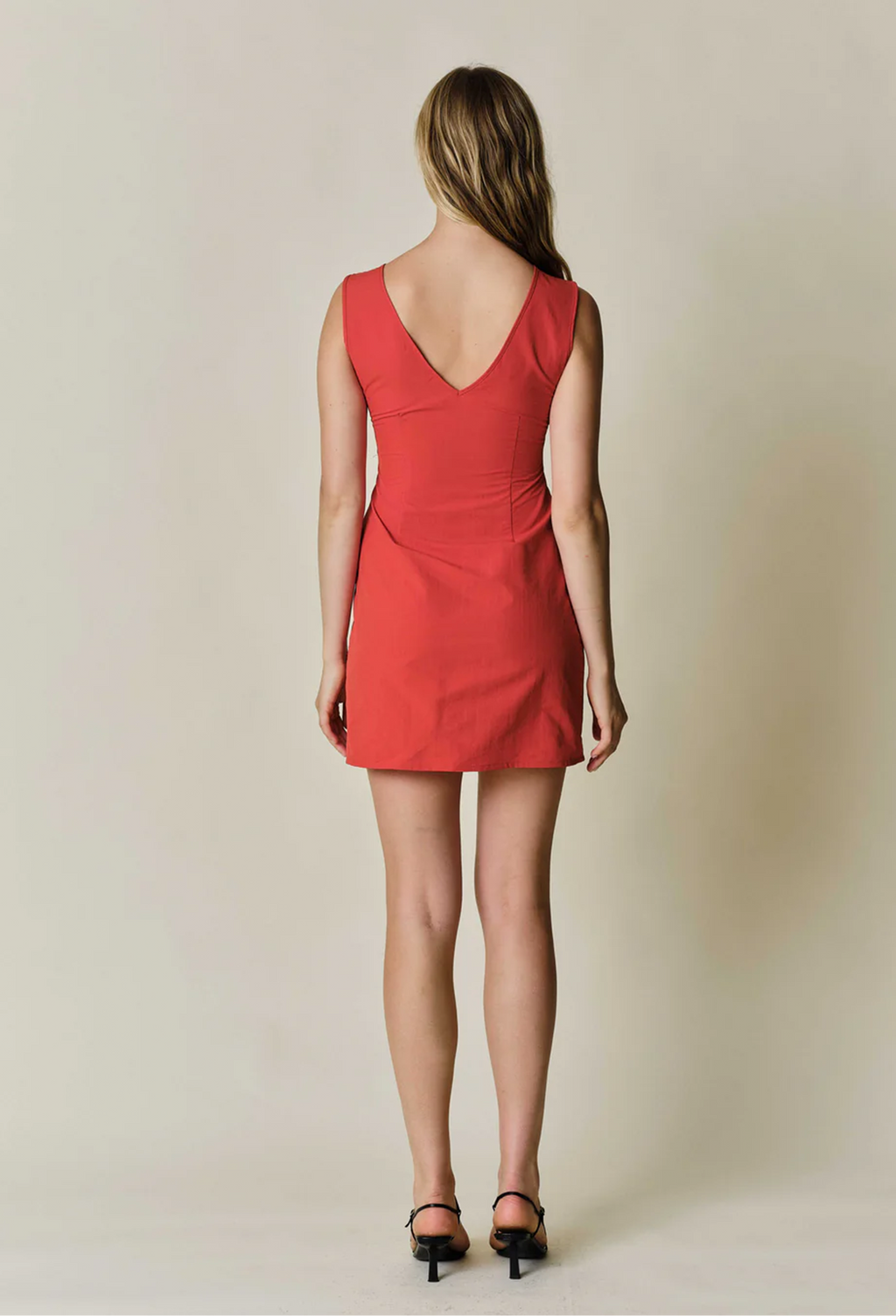 model wearing a sleeveless mini red dress on a white background