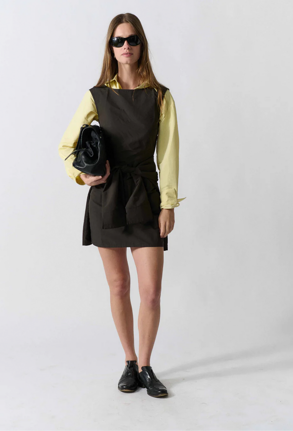 model wearing a sleeveless mini black dress on a white background