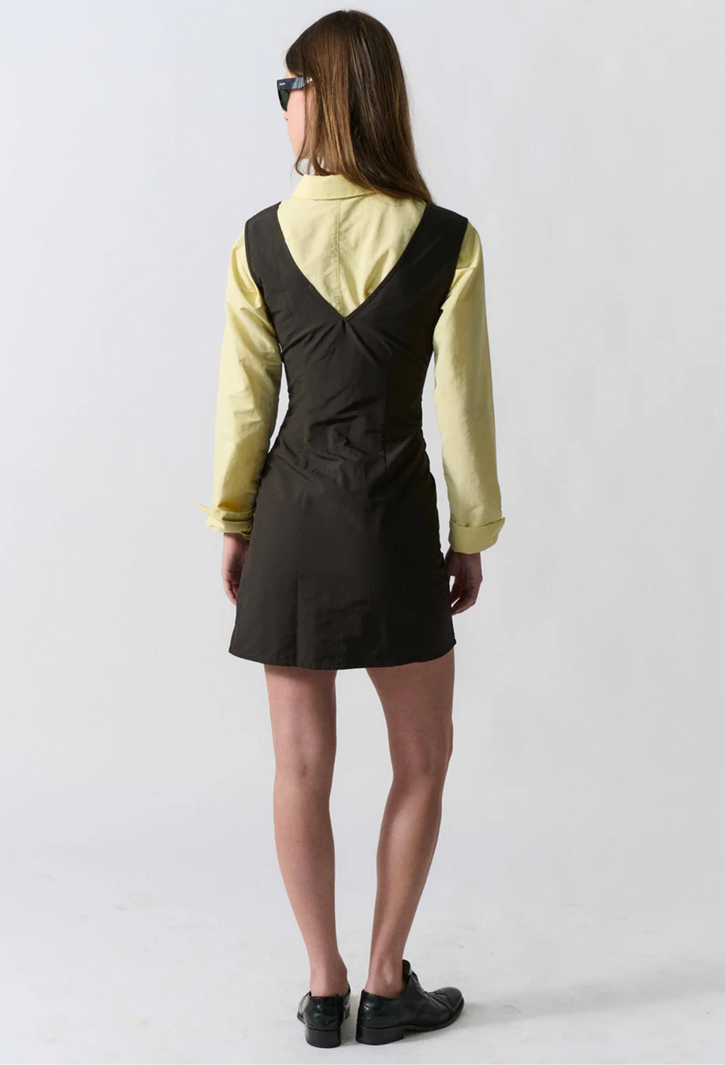 model wearing a sleeveless mini black dress on a white background