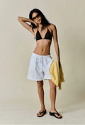 a model wearing white shorts with a drawstring waist on a beige background