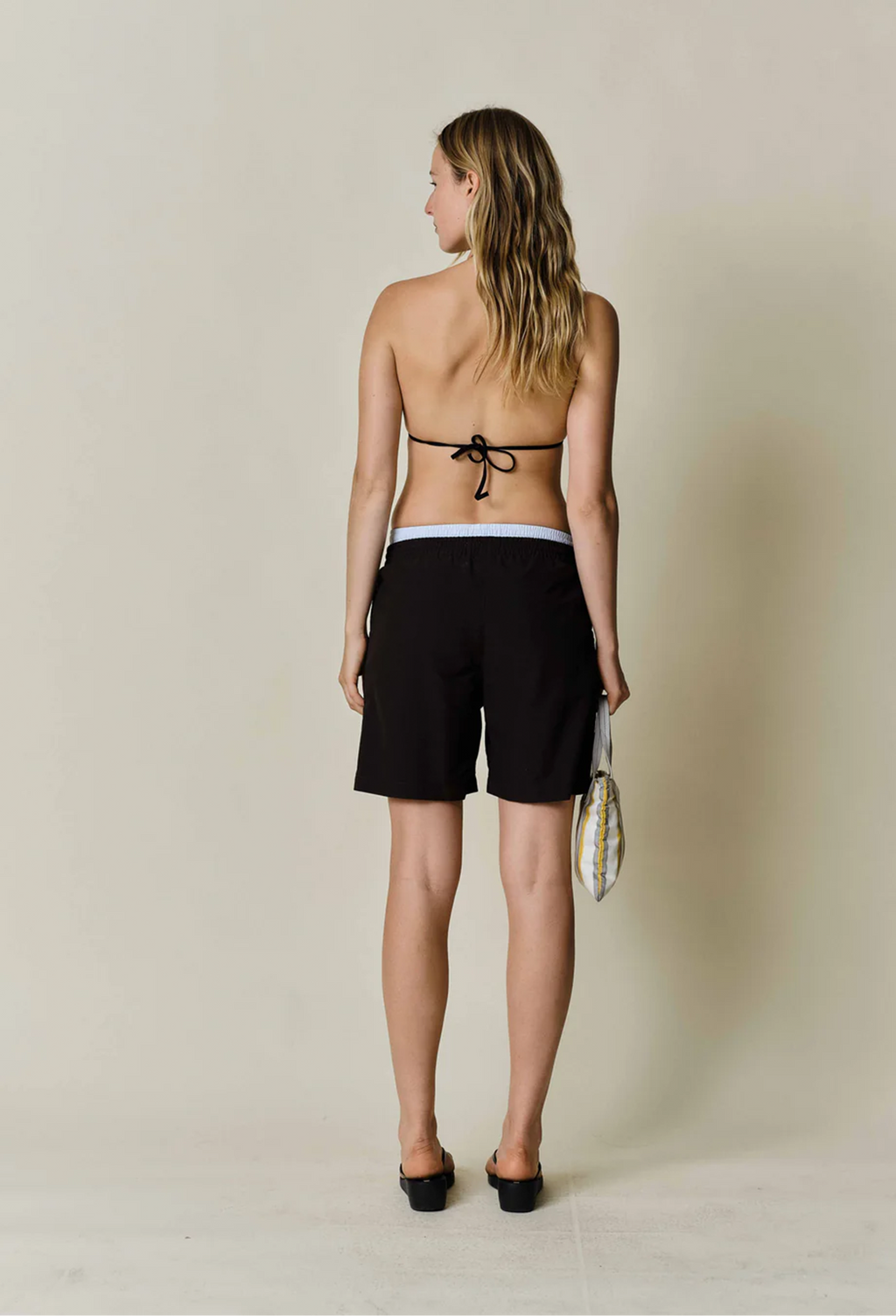 a model wearing black shorts with a drawstring waist on a beige background