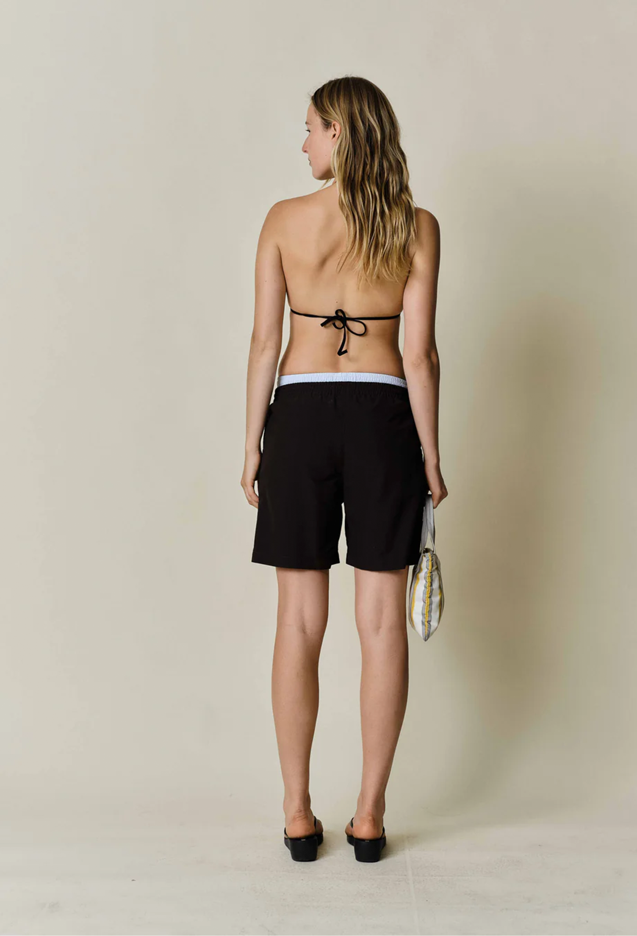 a model wearing black shorts with a drawstring waist on a beige background