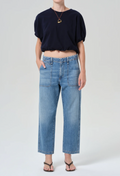 model wearing a blue top and jeans on a white background