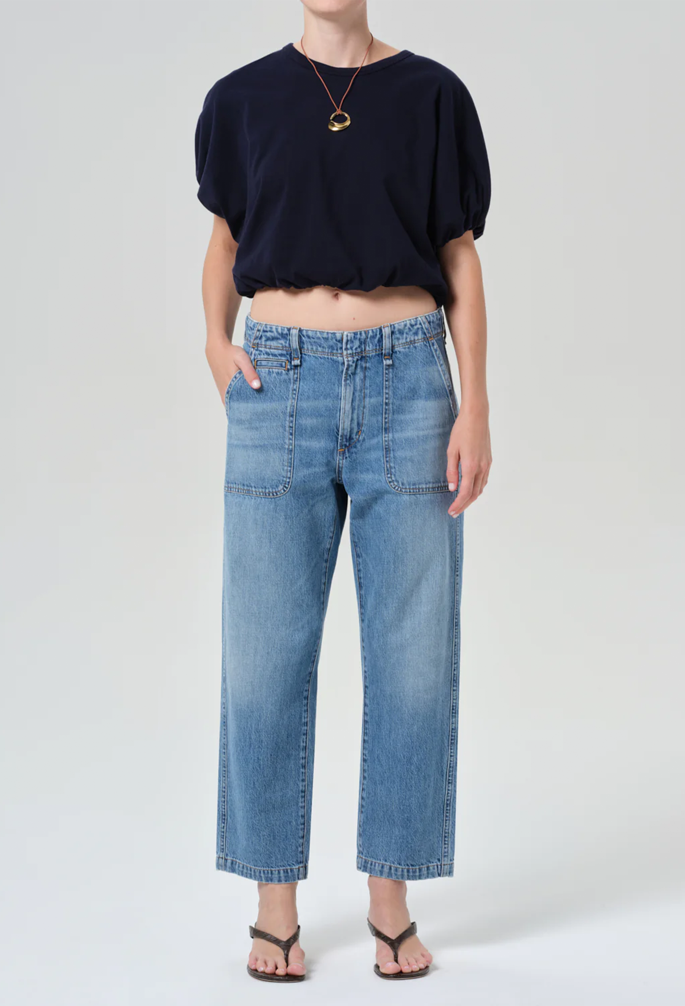 model wearing a blue top and jeans on a white background