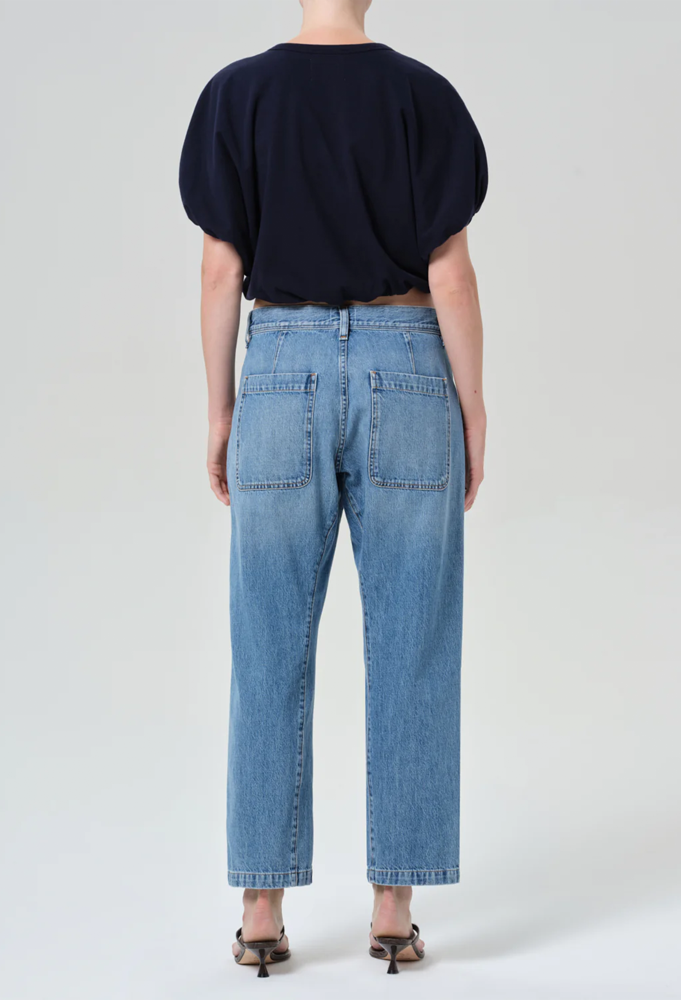 model wearing a blue top and jeans on a white background