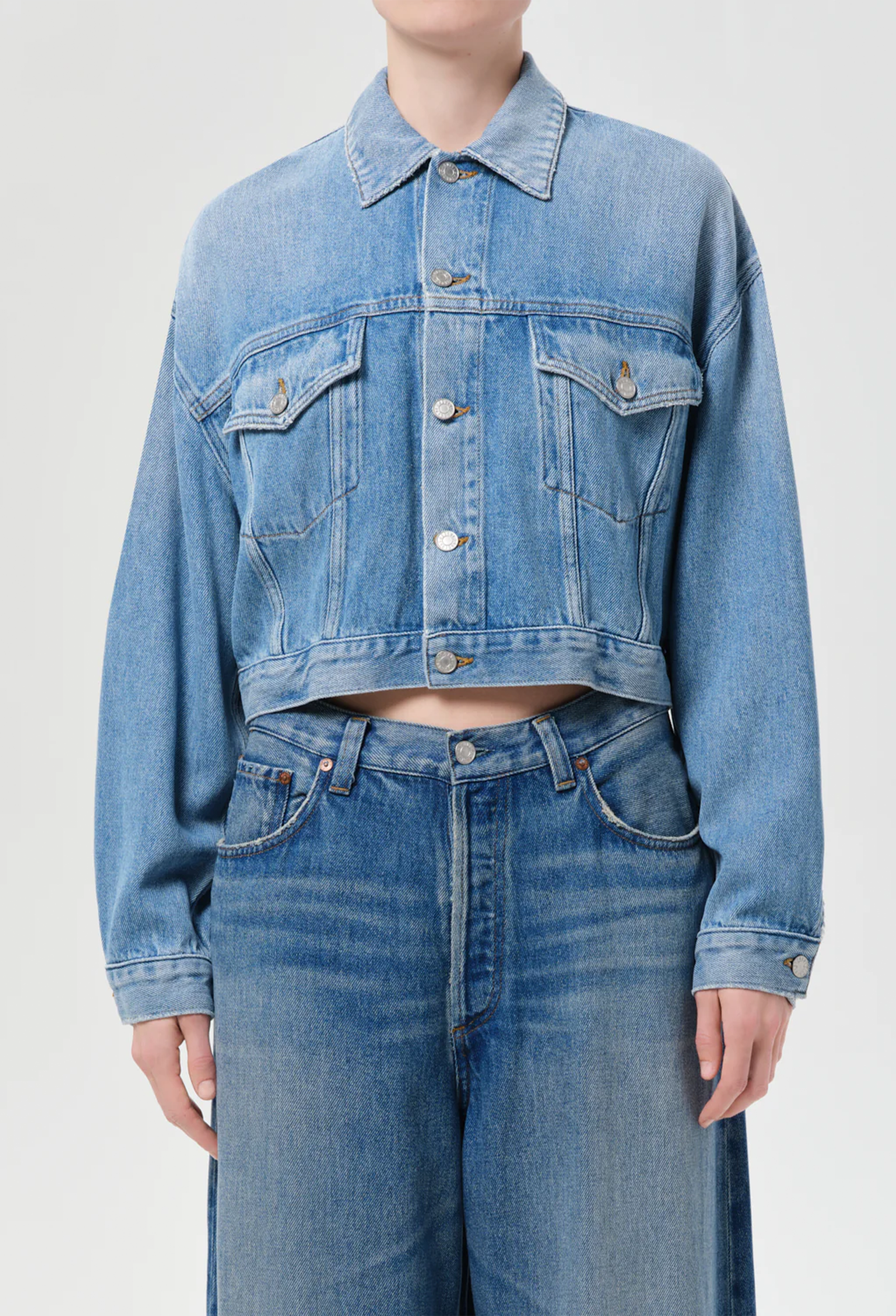 model wearing jeans and a denim jacket on a white background