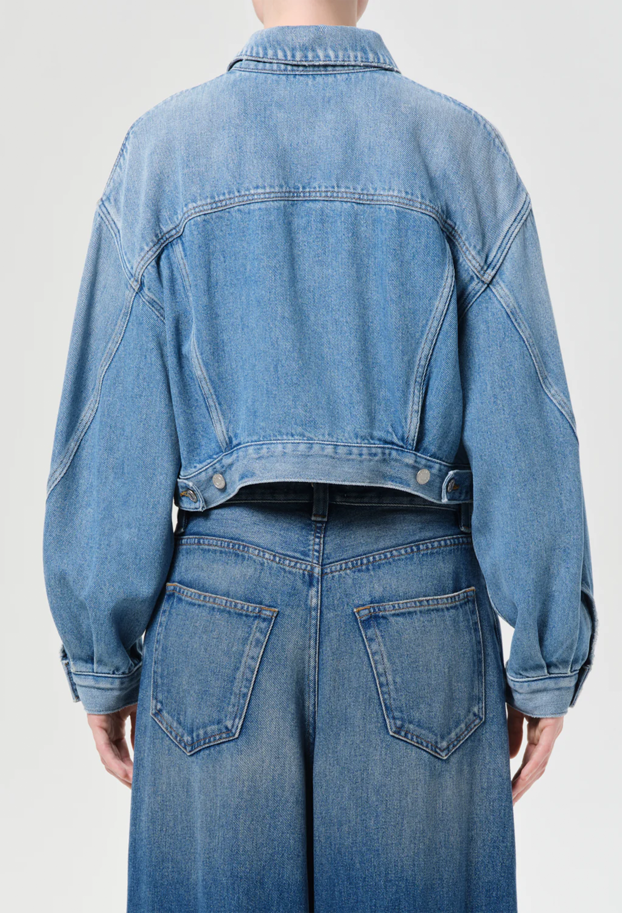 model wearing jeans and a denim jacket on a white background