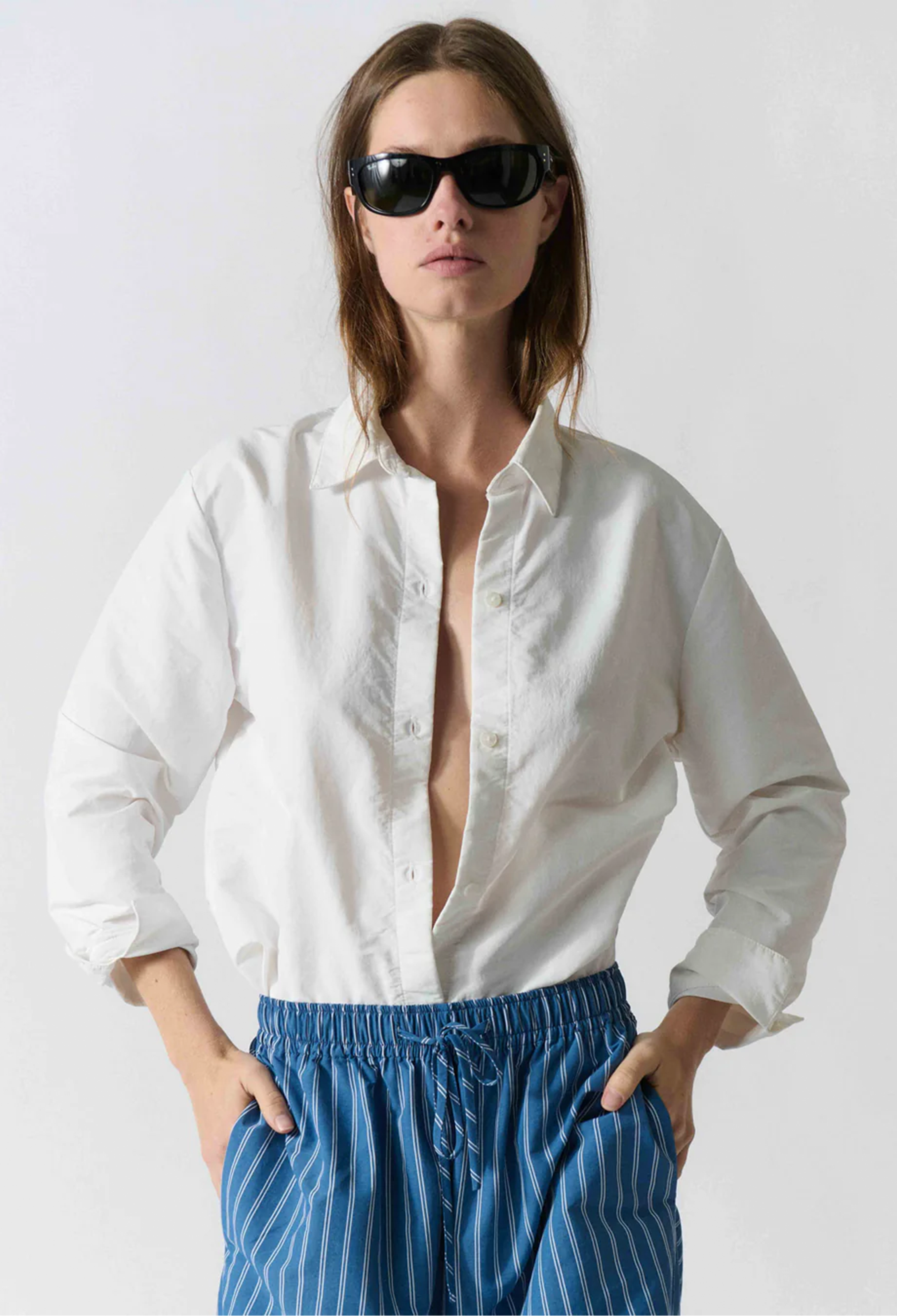 model wearing white button up shirt on a white background